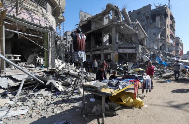 Palestinians shop near the ruins of houses and buildings destroyed in Israeli strikes during the conflict