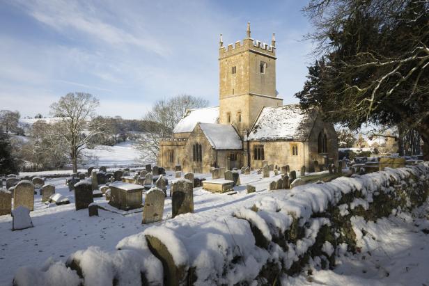 Eine verschneite Kirche mit Friedhof im Winter.