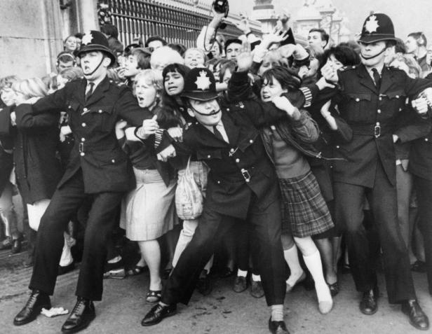 Britische Polizisten halten eine aufgeregte Menschenmenge zurück.