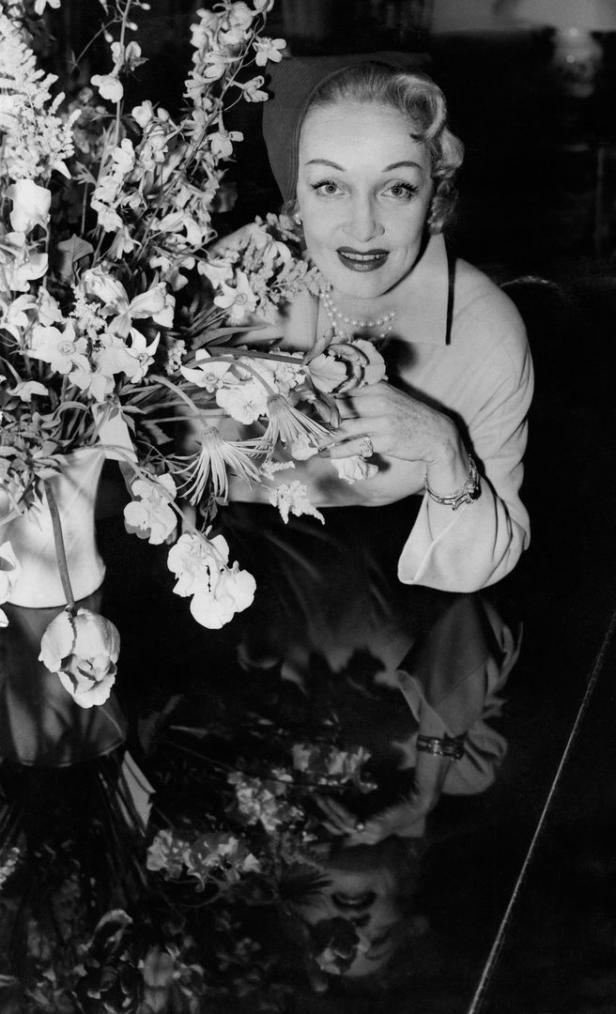 Marlene Dietrich posiert mit einem Blumenstrauß.
