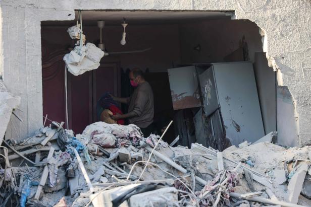 Ein Mann versucht, einige Habseligkeiten aus den Trümmern eines Gebäudes zu retten, das nach einem israelischen Bombenangriff in der Nacht zum 3. Dezember 2023 in Rafah im südlichen Gazastreifen zerstört wurde.