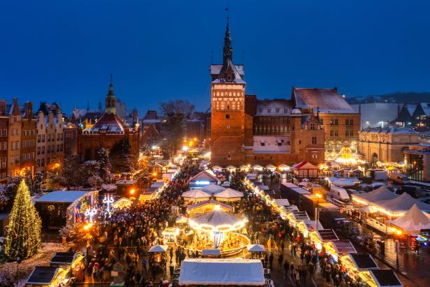 Blick auf den Weihnachtsmarkt in Danzig bei Nacht mit vielen Menschen und Lichtern.