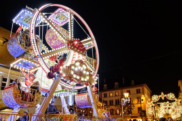 Ein beleuchtetes Riesenrad auf einem festlichen Weihnachtsmarkt bei Nacht.