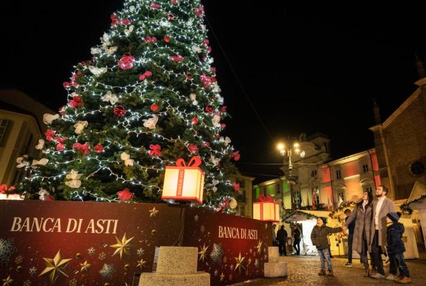 Ein Weihnachtsbaum mit Lichtern und Dekorationen steht auf einem Platz in Asti, Italien.