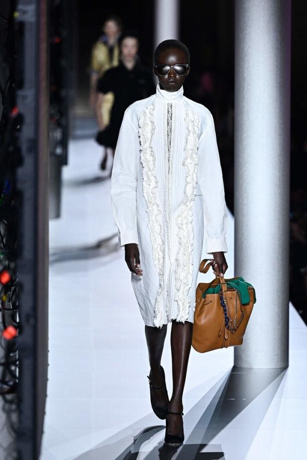 Ein Model präsentiert ein weißes Kleid und eine braune Handtasche bei der Miu Miu Spring 2024 Show.