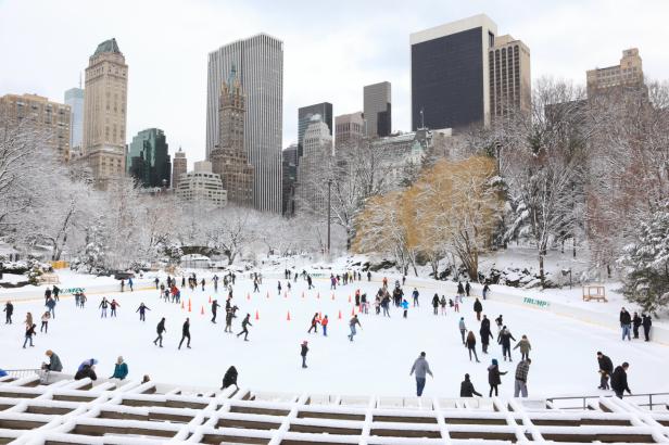 Menschen laufen auf einer Eisbahn im winterlichen New York vor der Skyline.