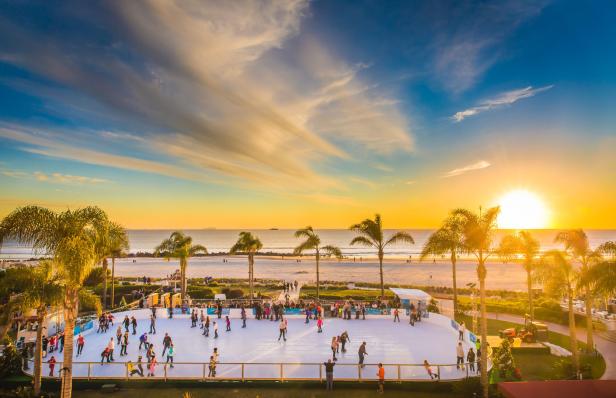 Menschen laufen bei Sonnenuntergang auf einer Eisbahn am Strand Schlittschuh.