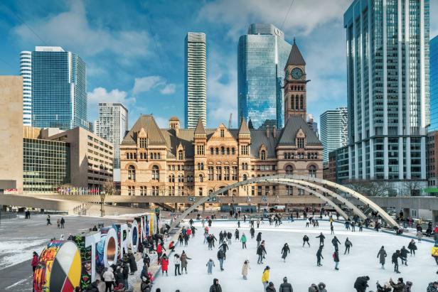 Menschen laufen auf der Eisbahn vor dem Rathaus von Toronto.