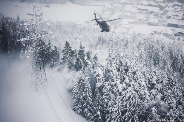 Ein S-70 "Black Hawk" befreit mit Hilfe seiner Down-Wash genannten Abwinde Bäume und Stromleitungen von der Schneelast.