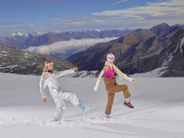 Zwei Frauen posieren in Winterkleidung vor einer Bergkulisse.
