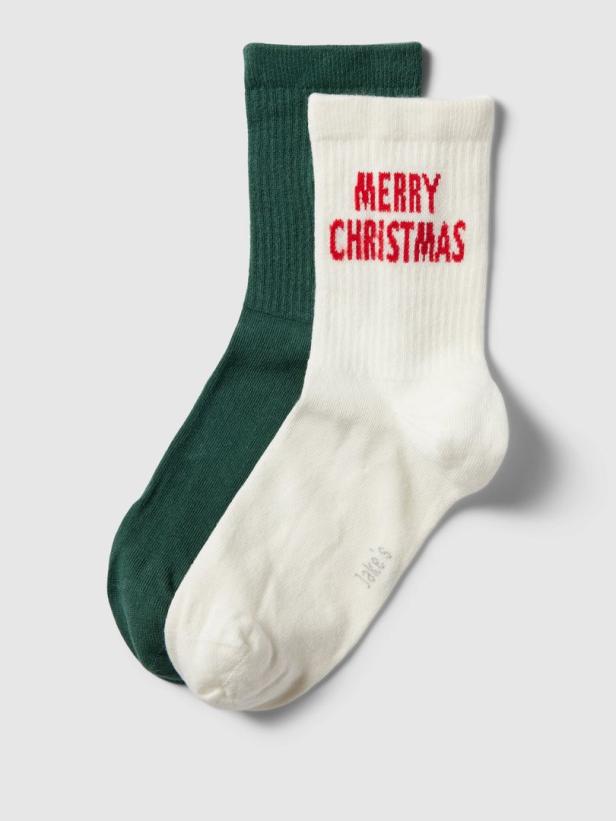 Ein Paar Socken, eine dunkelgrün, die andere weiß mit der Aufschrift „Merry Christmas“.