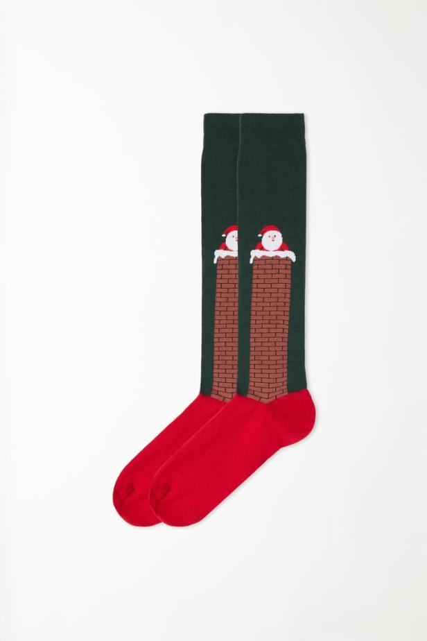 Ein Paar grüne und rote Socken mit einem Weihnachtsmann, der in einem Schornstein steckt.