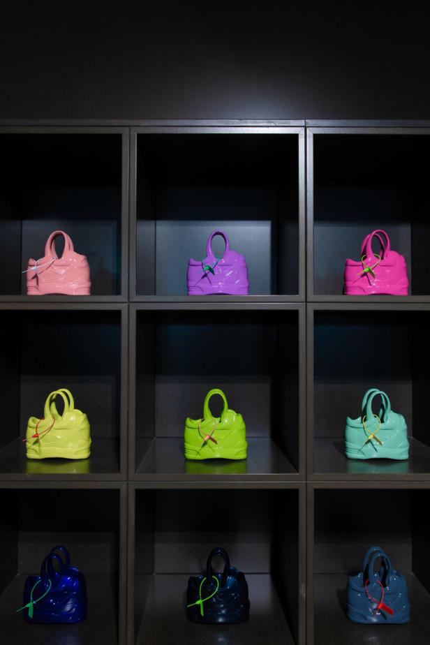Neun bunte Handtaschen in einem schwarzen Regal aus Würfeln.