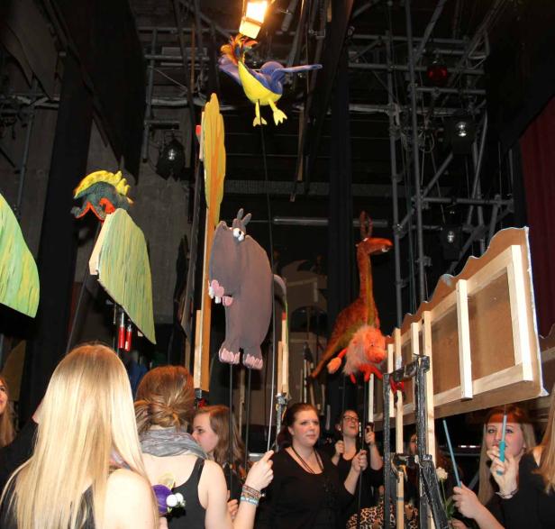 Puppenspielerinnen führen auf einer Bühne Tierpuppen vor.