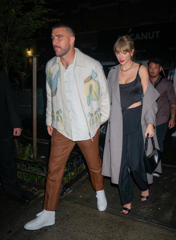 Taylor Swift und Travis Kelce verlassen gemeinsam ein Gebäude.