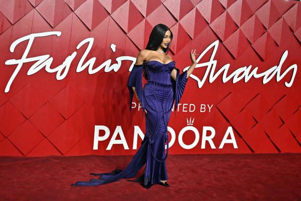 Eine Frau in einem lila Kleid posiert vor dem Hintergrund der „Fashion Awards“.