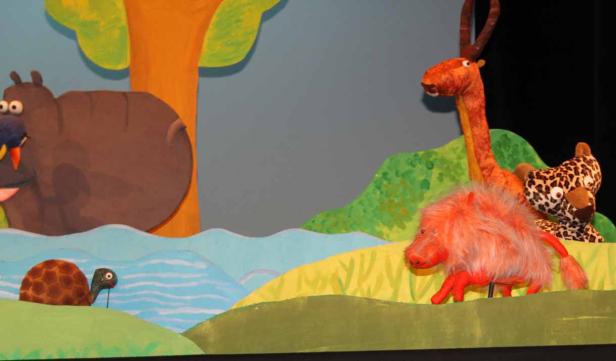 Eine bunte Puppenspielszene mit Nilpferd, Schildkröte, Stachelschwein, Giraffe und Leopard.
