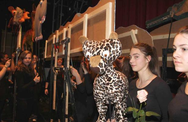 Hinter der Bühne eines Theaters werden Puppen und Kulissen für eine Aufführung vorbereitet.