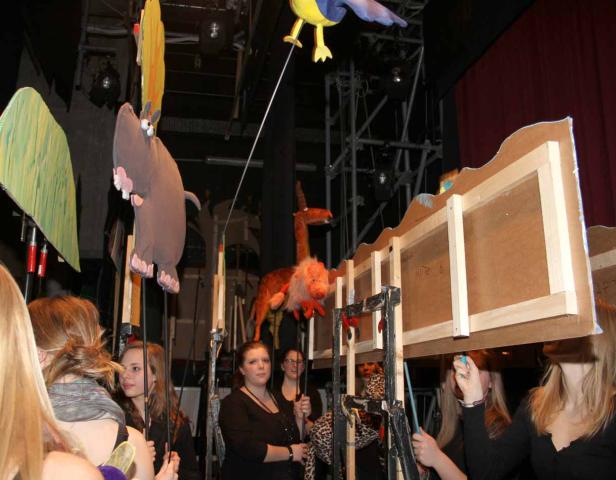 Eine Gruppe von Menschen bedient Marionetten auf einer Bühne.