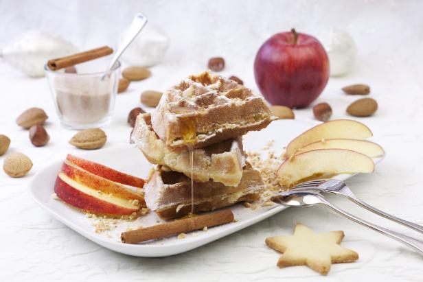 Ein Teller mit Waffeln, Apfelspalten, Zimtstangen und einem Sternförmigen Keks.