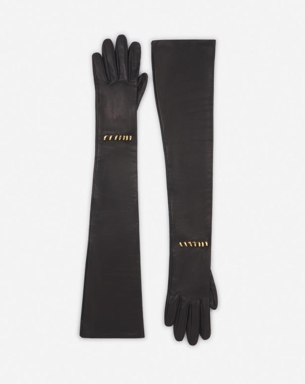Zwei lange, schwarze Lederhandschuhe mit goldenen Akzenten liegen auf einem weißen Hintergrund.