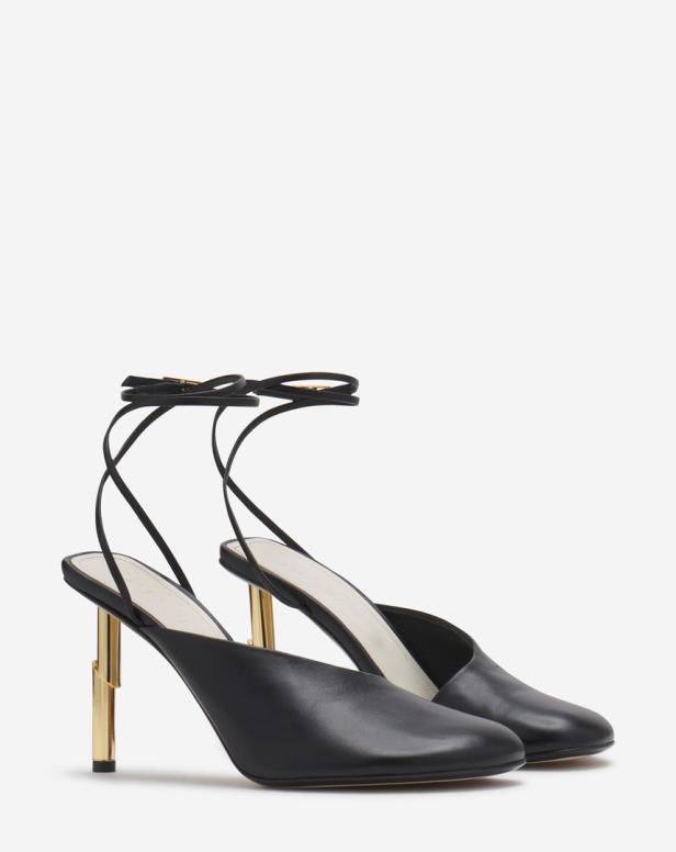 Ein Paar schwarze Lederschuhe mit goldenen Absätzen und Knöchelriemen.