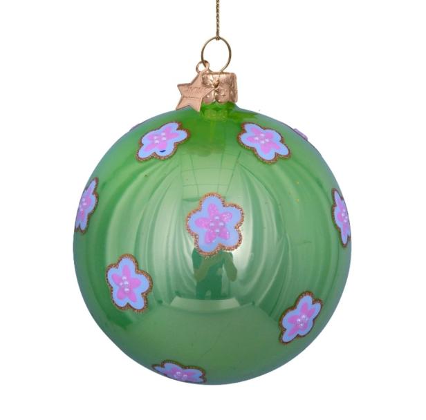 Eine grüne Weihnachtskugel mit rosa Blumenmuster hängt an einem goldenen Faden.