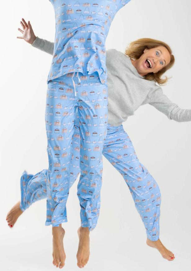 Zwei Frauen springen und tragen passende hellblaue Pyjamas mit Handtaschenmuster.