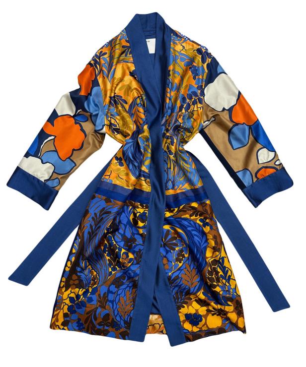 Ein floral gemusterter Morgenmantel in Blau, Orange und Gold liegt auf einem weißen Hintergrund.