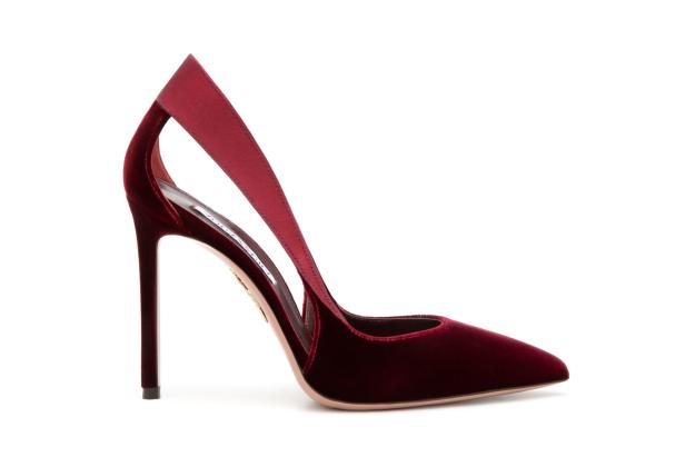 Ein roter, hochhackiger Damenschuh aus Samt vor einem weißen Hintergrund.