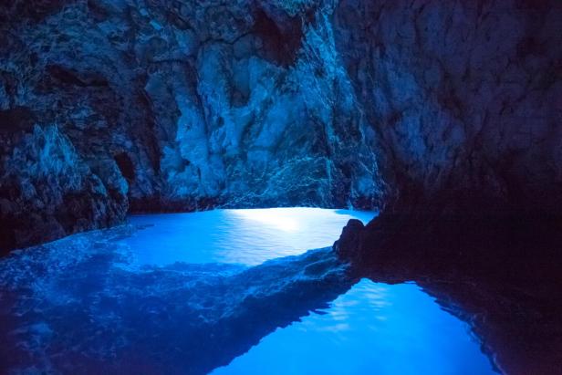 Blaues Wasser in einer dunklen Höhle mit Felswänden.