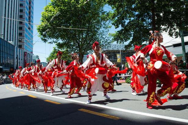 Eine Gruppe von Menschen in traditionellen Kostümen tanzt auf einer Straße.