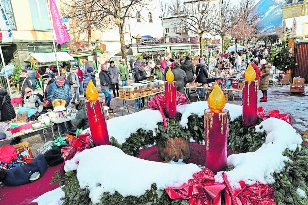 Ein Weihnachtsmarkt mit einem großen Adventskranz im Vordergrund.