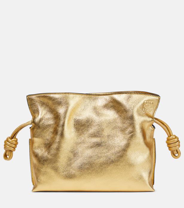Eine goldfarbene Loewe Flamenco Clutch liegt vor einem neutralen Hintergrund.