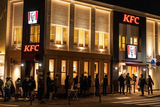 Tokio am Abend des 24. Dezember 2022: Viele Menschen warten vor einem hell erleuchteten Restaurant der Kette "Kentucky Fried Chicken"