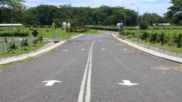 Eine asphaltierte Straße mit Pfeilen, die die Fahrtrichtung anzeigen.