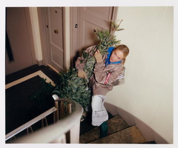 Eine Frau trägt einen Weihnachtsbaum die Treppe hinauf.
