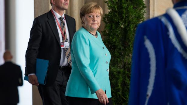 Angela Merkel bei einer Veranstaltung, begleitet von einem Sicherheitsbeamten.