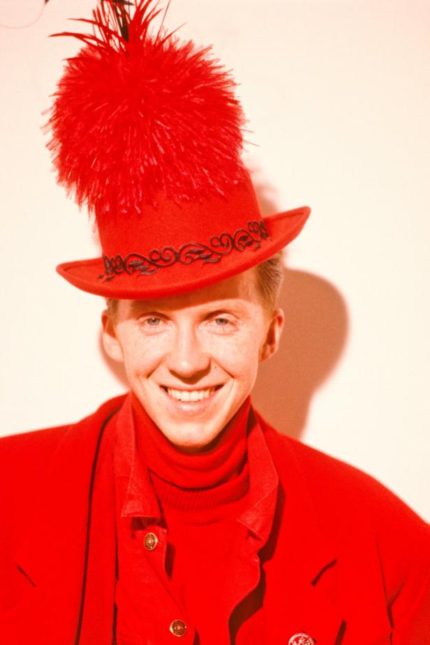 Ein lächelnder Mann mit rotem Hut und passendem Outfit.