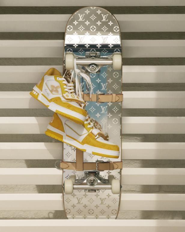 Ein Skateboard mit Louis Vuitton-Muster und gelb-weiße Schuhe darauf.