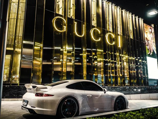 Ein weißer Porsche parkt vor einem Gucci-Geschäft.