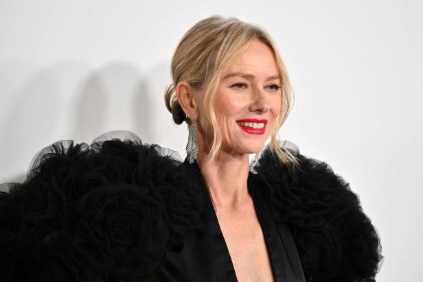 Naomi Watts trägt ein schwarzes Kleid mit Rüschen und roten Lippenstift.