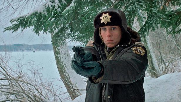 Eine Polizistin zielt mit einer Waffe in einer verschneiten Landschaft.