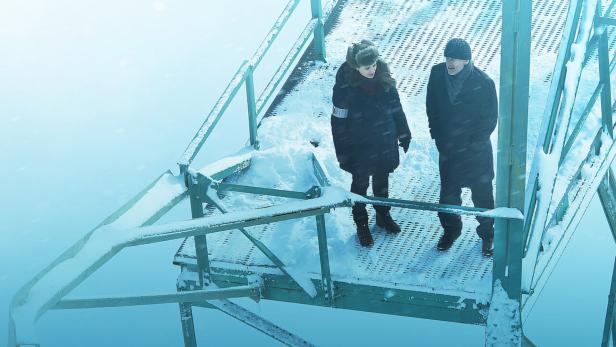 Zwei Personen stehen auf einer schneebedeckten Plattform im Freien.
