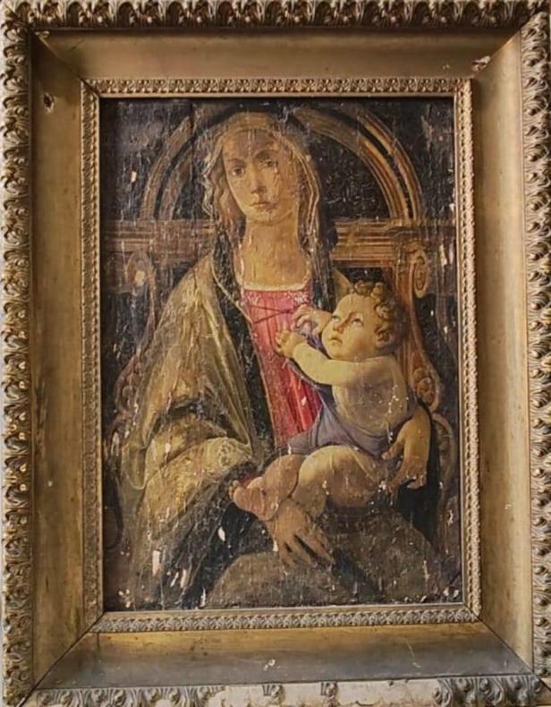 Eine beschädigte Darstellung der Madonna mit Kind in einem goldenen Rahmen.
