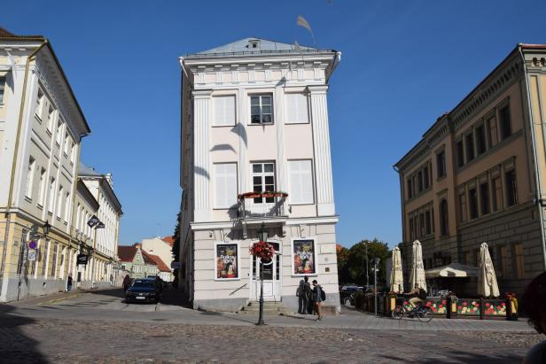 Schiefes Haus in Tartu Ein hohes, schlankes Gebäude mit klassischer Fassade in einer Stadtstraße.