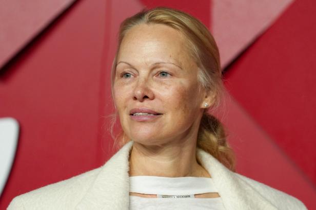 Pamela Anderson vor einem roten Hintergrund.