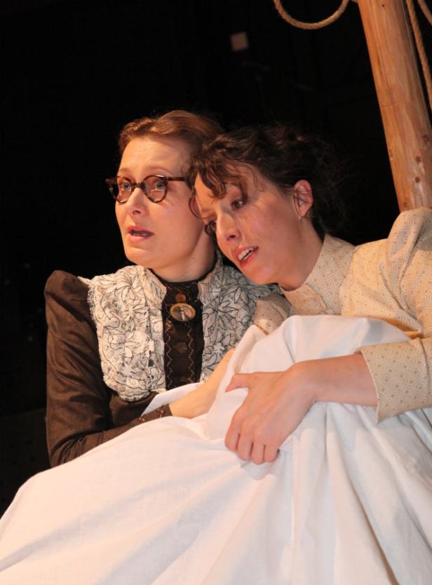 Zwei Frauen in Kostümen auf einer Theaterbühne.