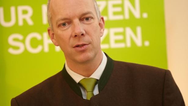 Ein Mann mit Trachtenjacke und grünem Schlips vor einem grünen Hintergrund.