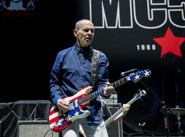 Wayne Kramer spielt Gitarre mit einem Design der US-Flagge auf der Bühne.